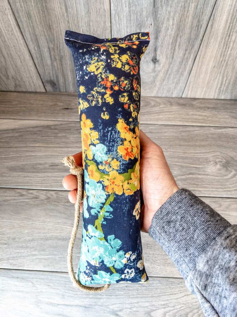 A hand holding a catnip kicker made from a blue Japanese cherry blossom themed fabric