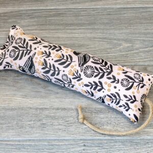 A catnip kicker made from a grey fabric black birds and foliage patterns on it
