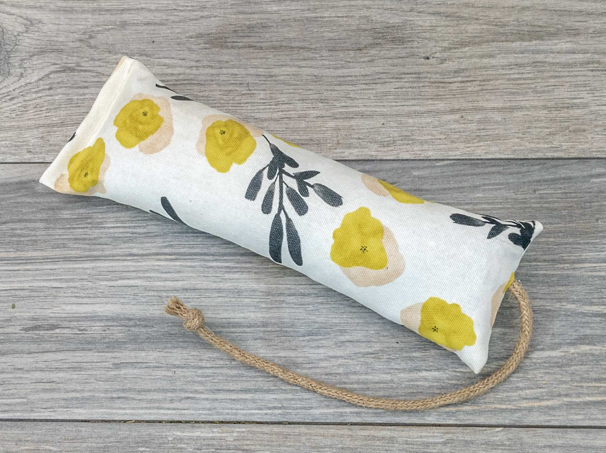A catnip kicker made from a white fabric with yellow flower and green spring of foliage print