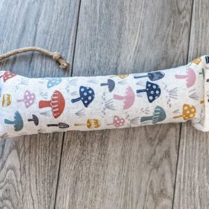 A catnip kicker made from a white fabric with various mushrooms printed o nit. 