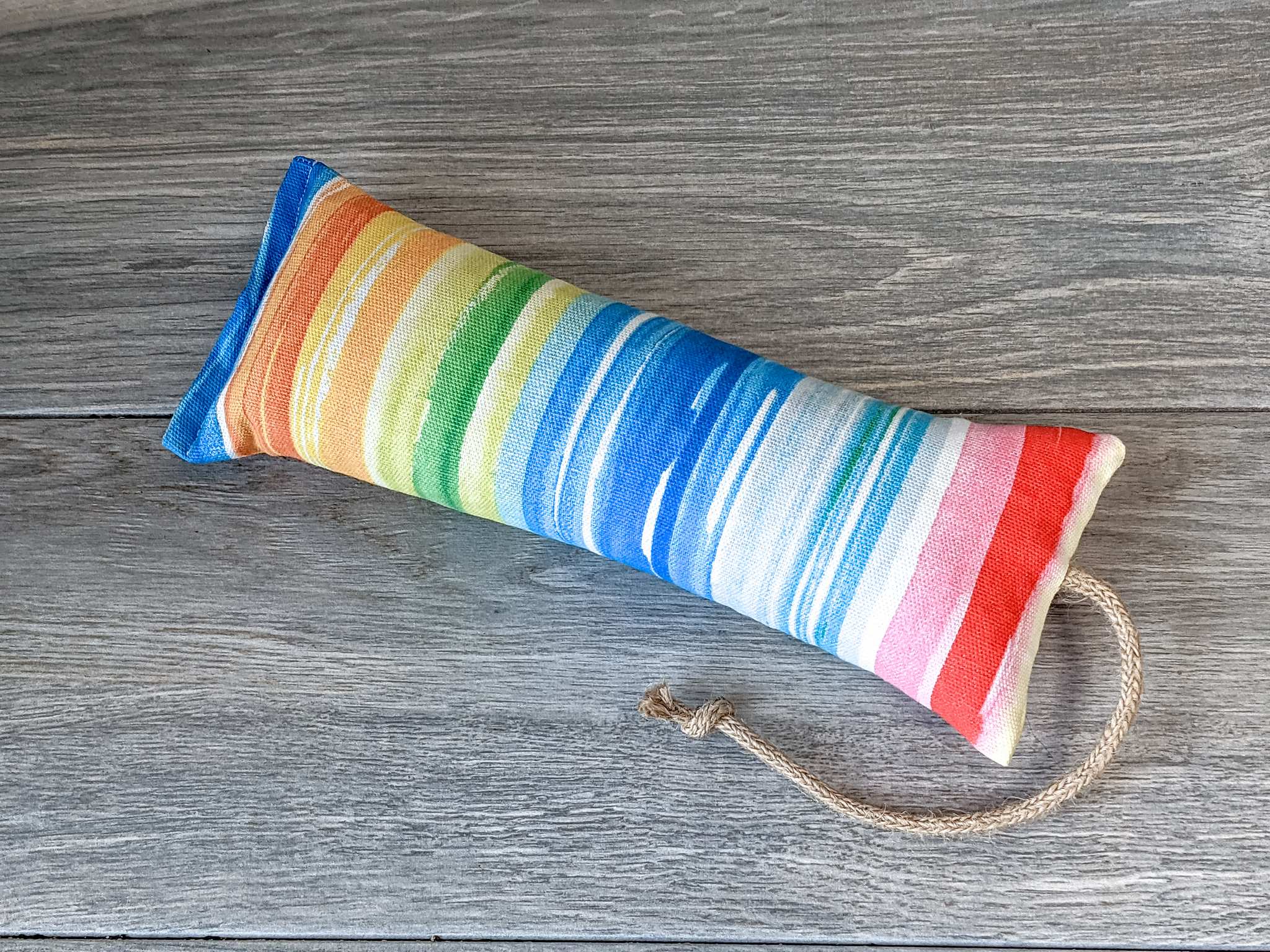 A catnip kicker made out of a fabric that looks like a watercolor rainbow stuffed with catnip