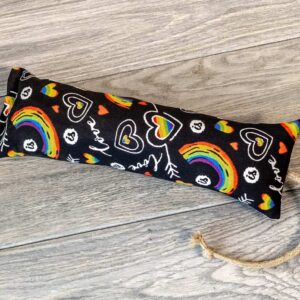 A catnip kicker made from a black fabric that has a pattern of rainbows and the word "love" on it. 