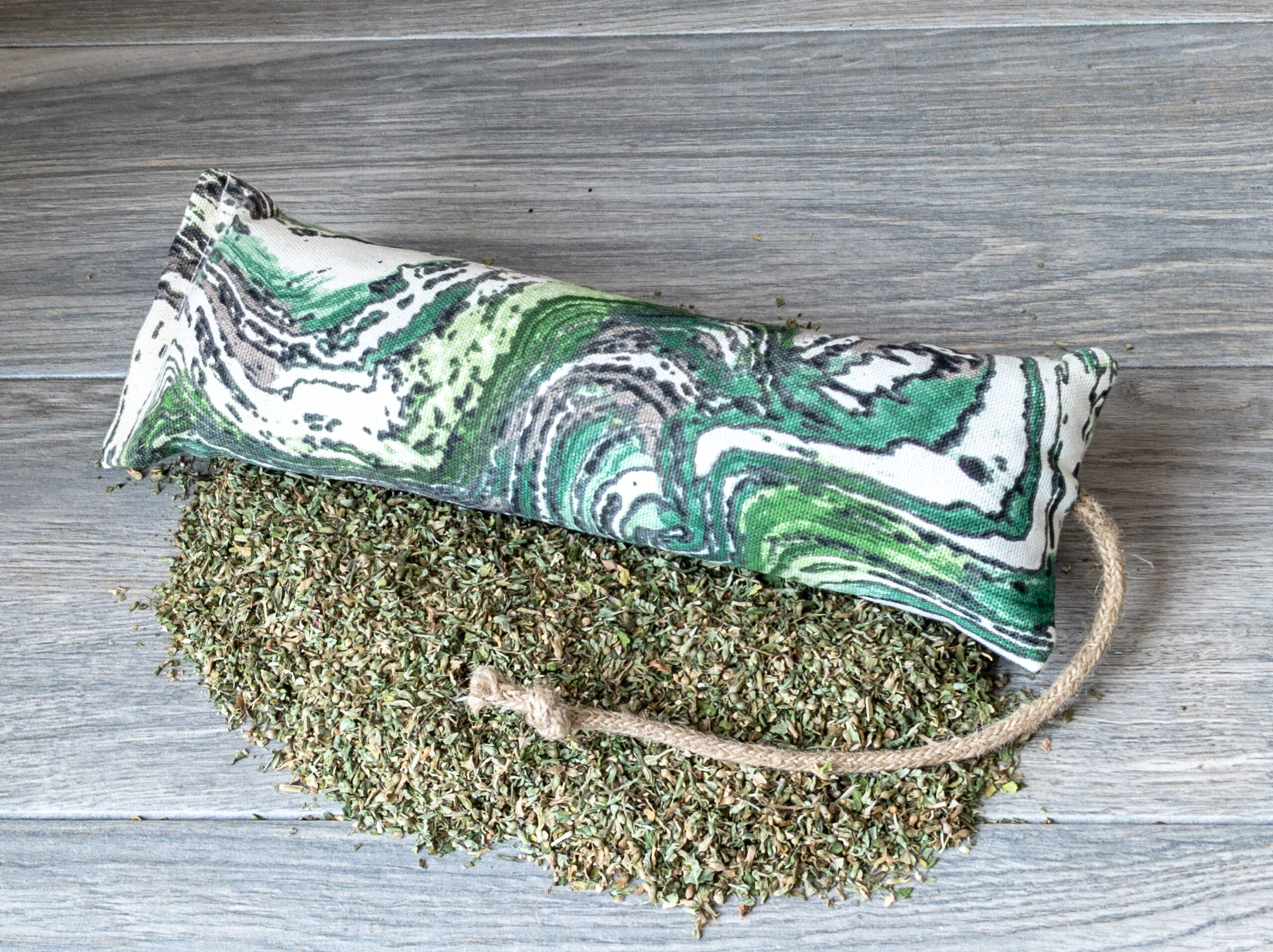 A catnip kicker made of green geode fabric on a pile of catnip