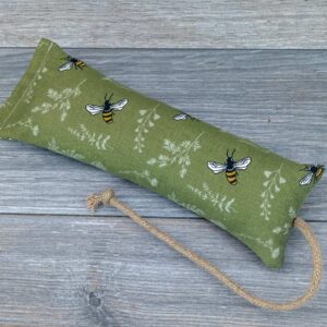 A catnip kicker made of green fabric with bees on it