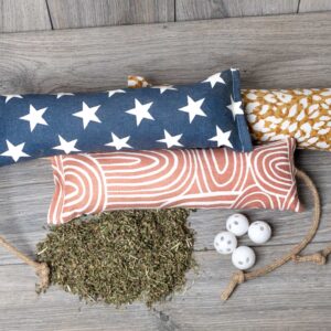 Three kickers in different patterns with a pile of catnip and white rattles