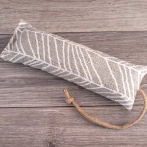 A hand holding a catnip kicker made out of a white woodland themed fabric.