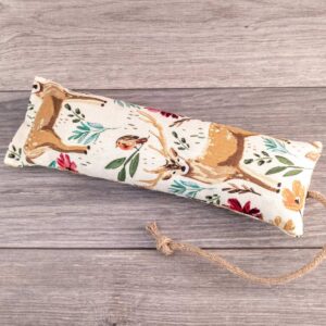 A hand holding a catnip kicker made out of a white woodland themed fabric.