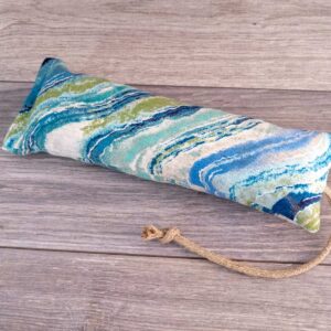 A hand holding a catnip kicker made out of a blue and white natural striped fabric.