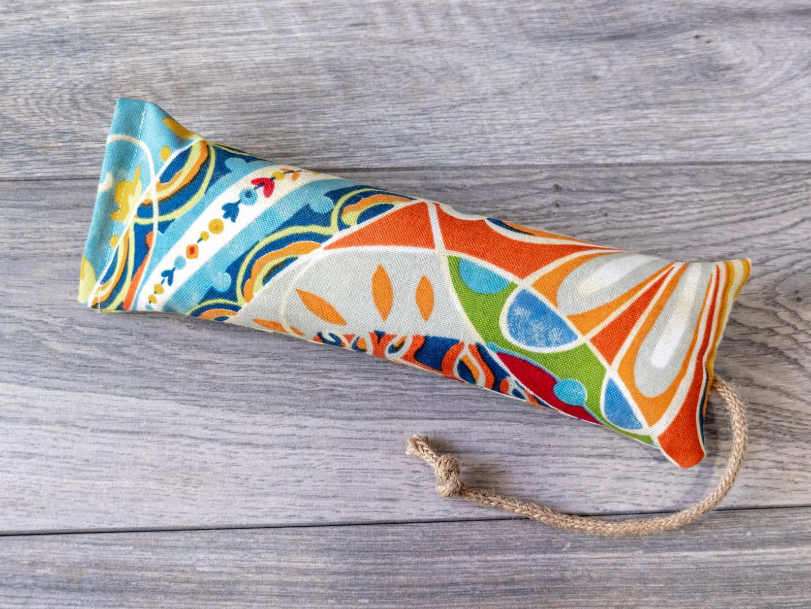 A catnip kicker cat toy made out of a fabric with a multi color maximalist print