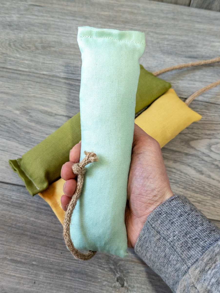 A hand holding a blue green catnip kicker