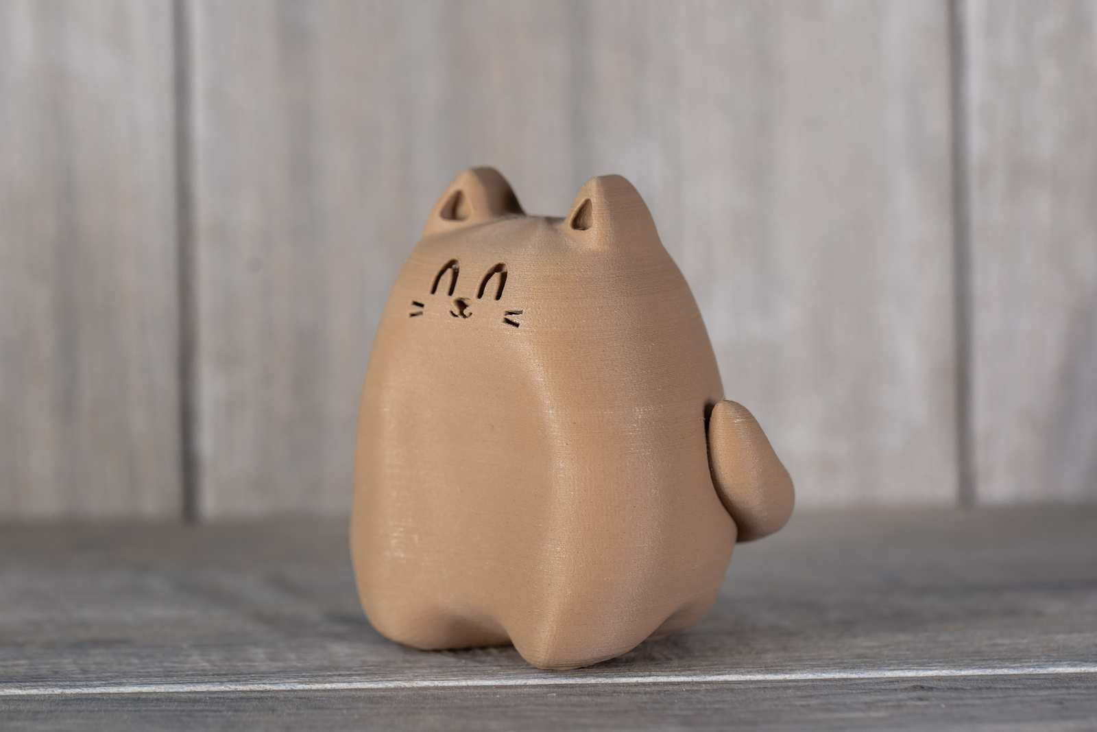 A small figure of a 3D printed cat that looks like wood