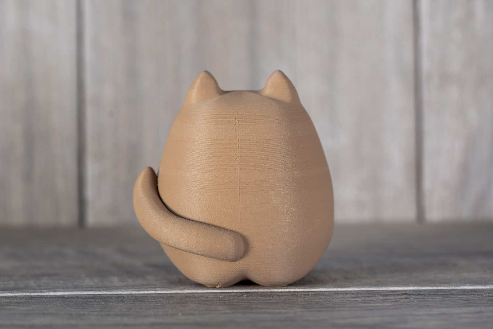 A small figure of a 3D printed cat that looks like wood