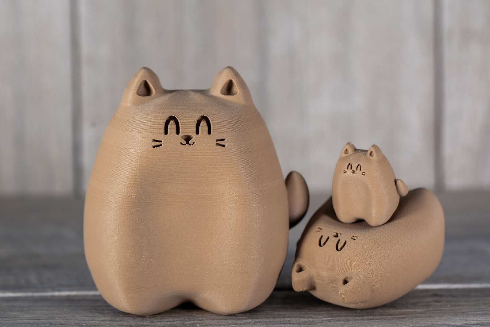 Various sizes of figures of 3D printed cats that looks like wood