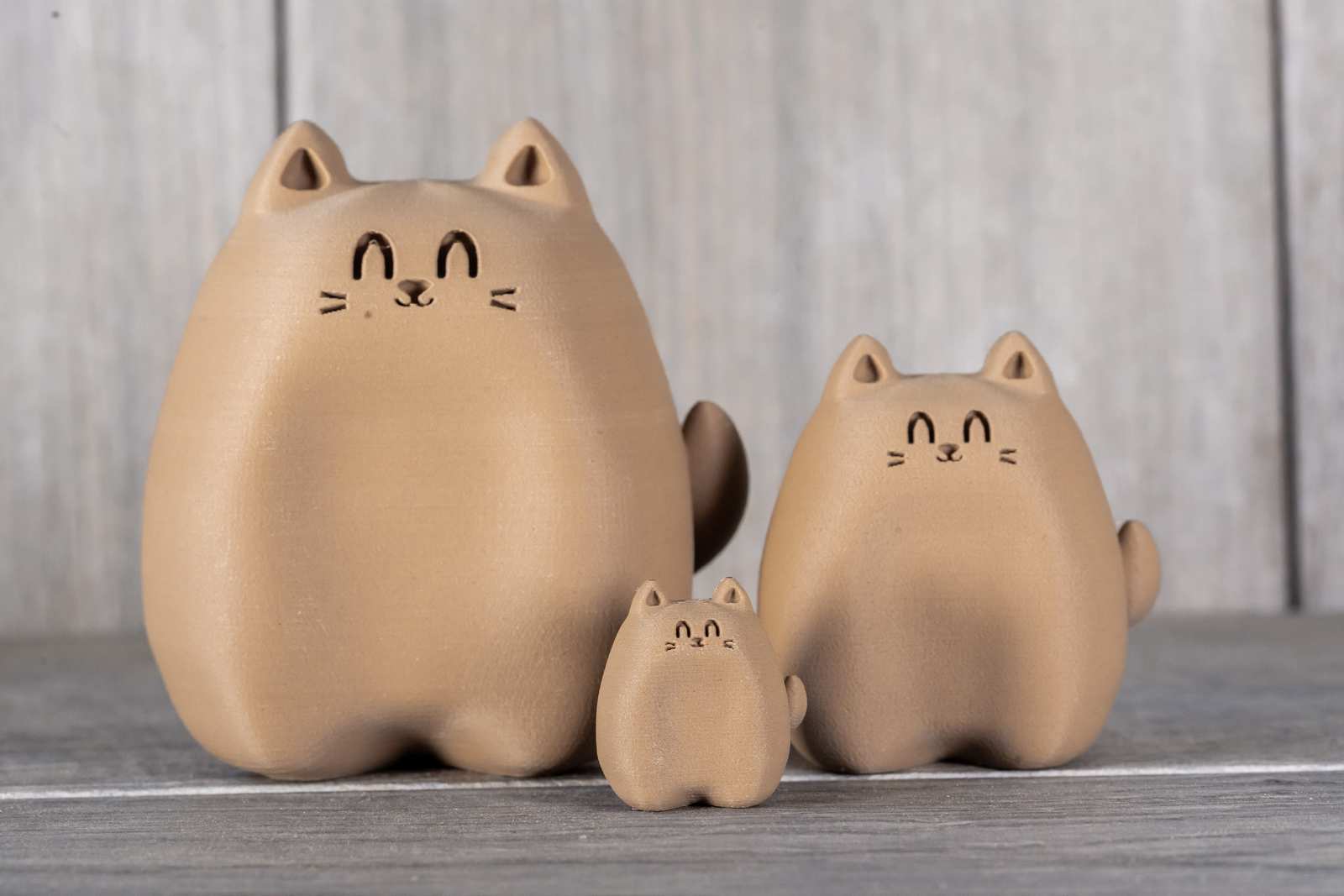 Various sizes of figures of 3D printed cats that looks like wood