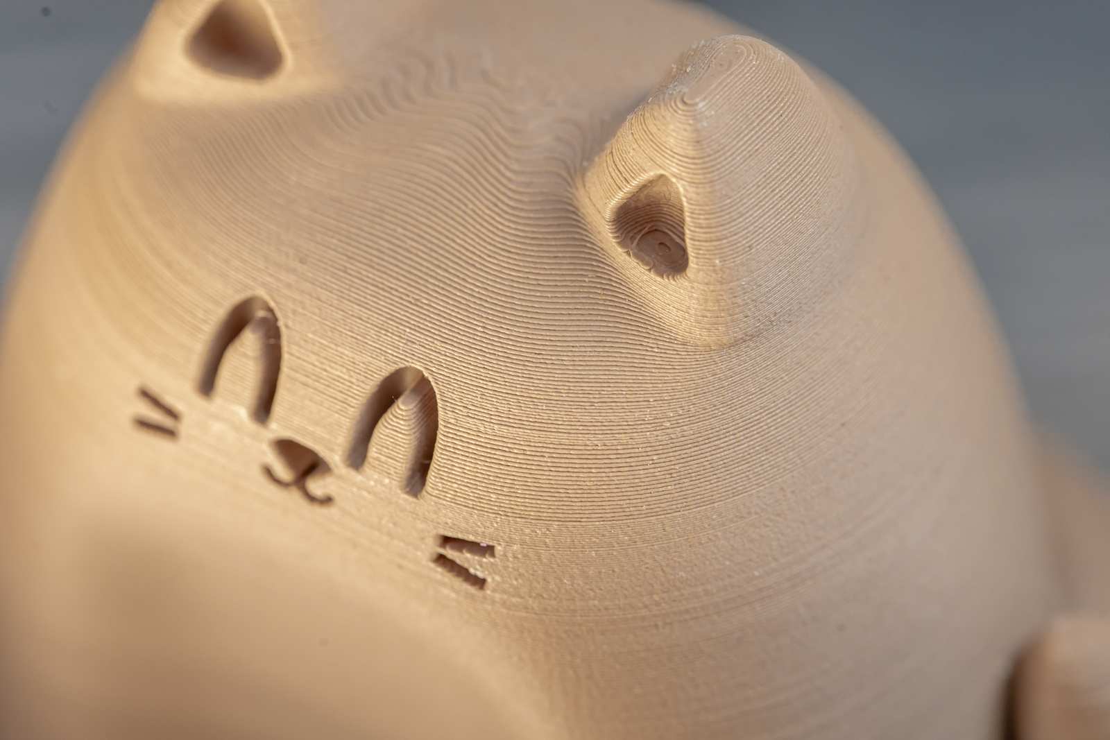 A small figure of a 3D printed cat that looks like wood