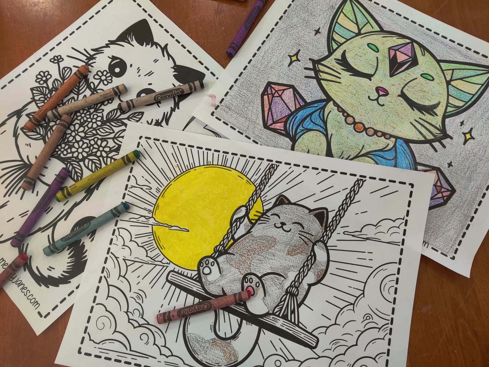 Coloring pages on a table that are partially colored in with crayon