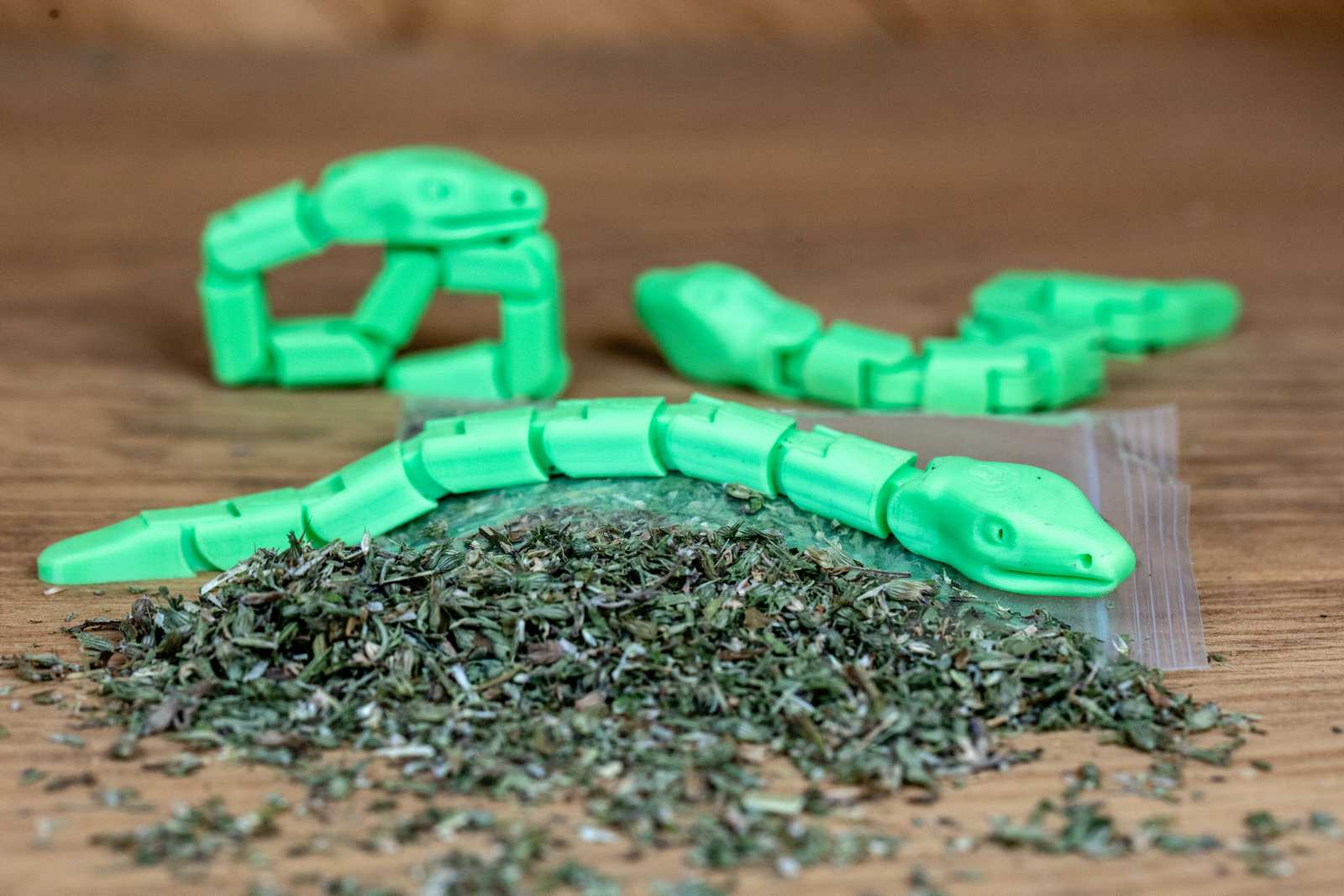 Green articulated snake toys in various positions with piles of catnip