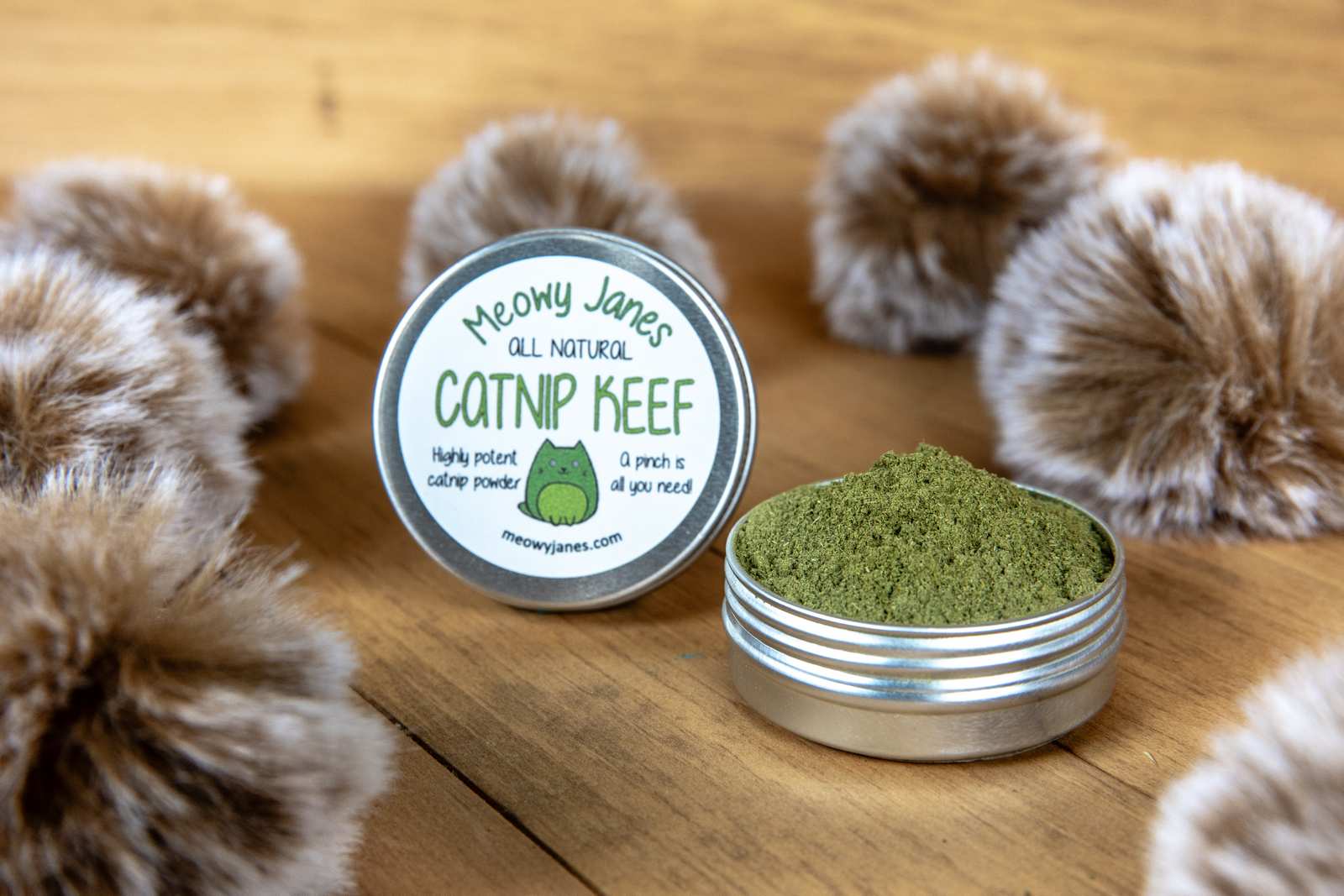 A tin of catnip powder with fuzzy pom pom toys