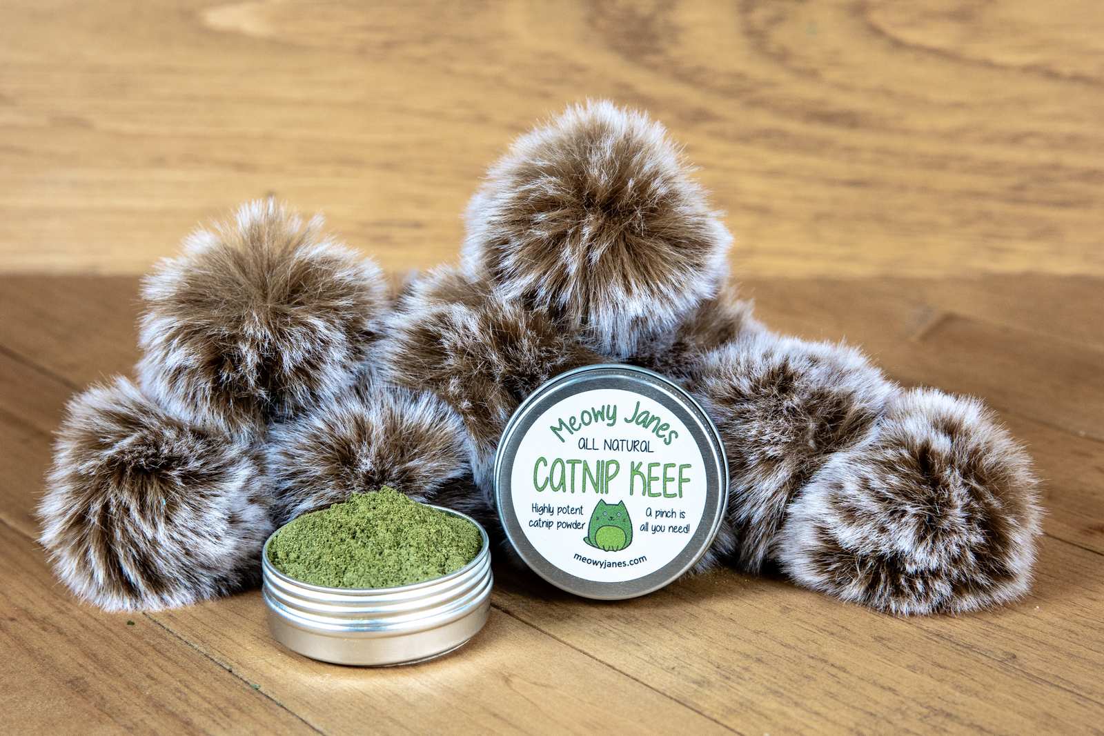 A tin of catnip powder with fuzzy pom pom toys
