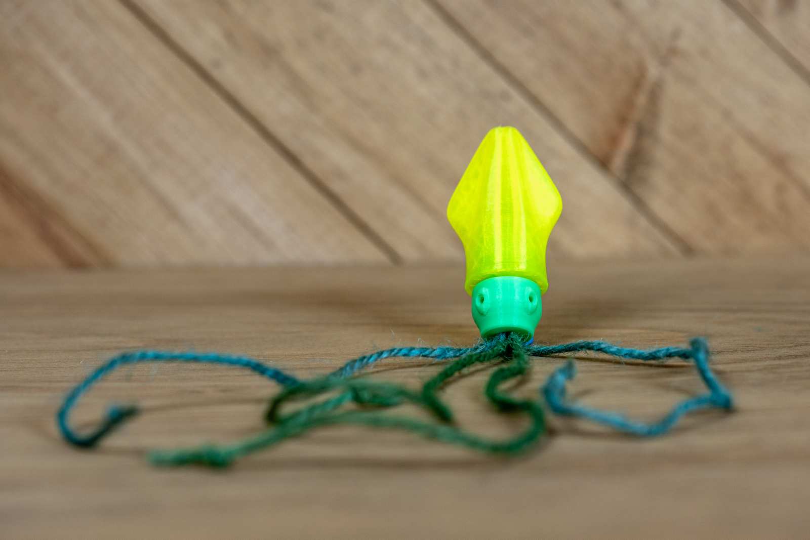 A cat toy that looks like a small squid with yellow body, green head, and jute tentacles.