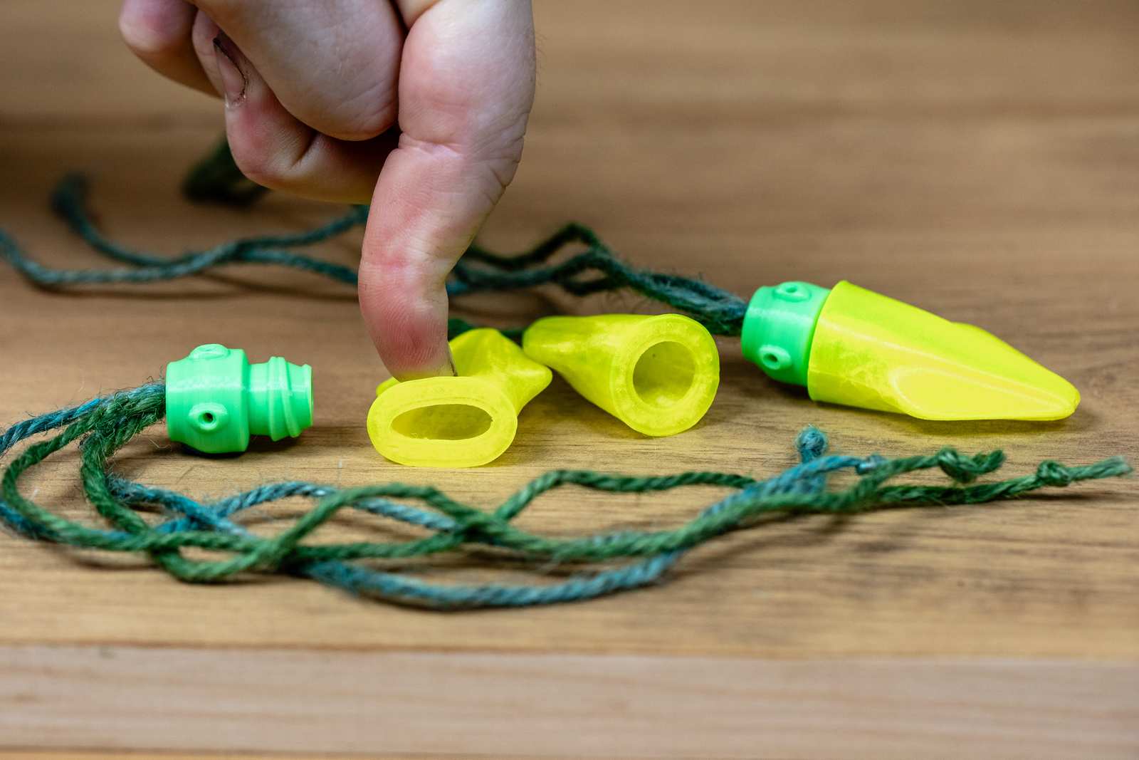 A cat toy that looks like a small squid with yellow body, green head, and jute tentacles. Head is removed from the body with a finger showing it is squishy