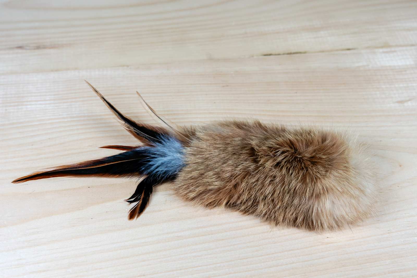 A rectangular cat toy made of rabbit fur and feathers