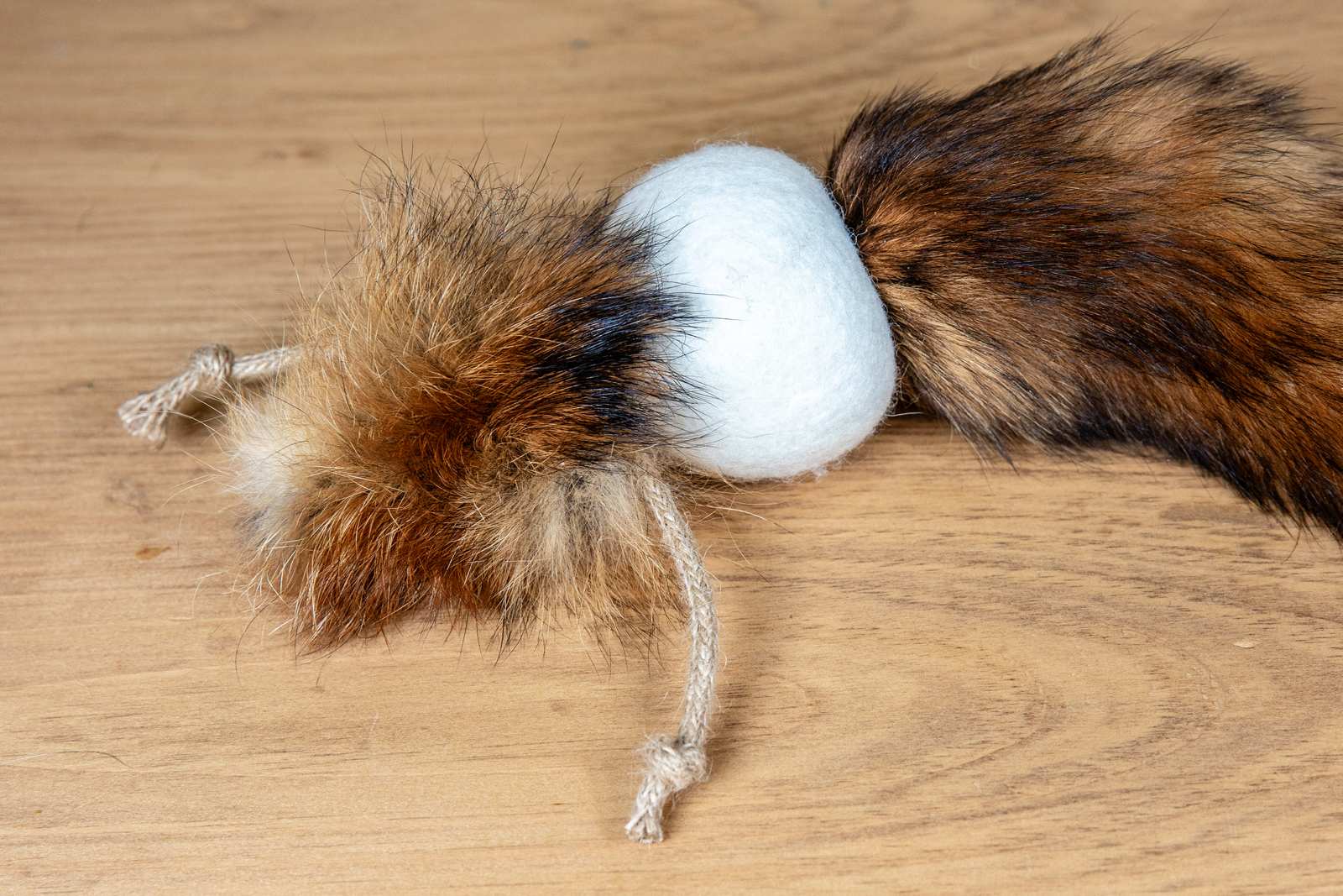 A orange cat toy made out of a fox tail attached to a wool ball